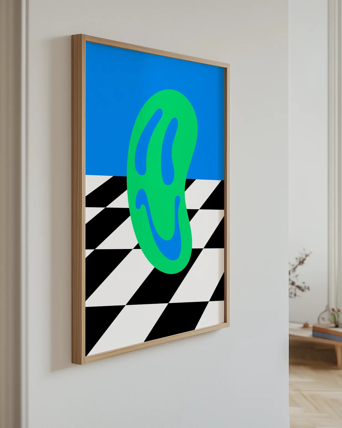 Art piece with a green smiley on a blue background, framed in a room.