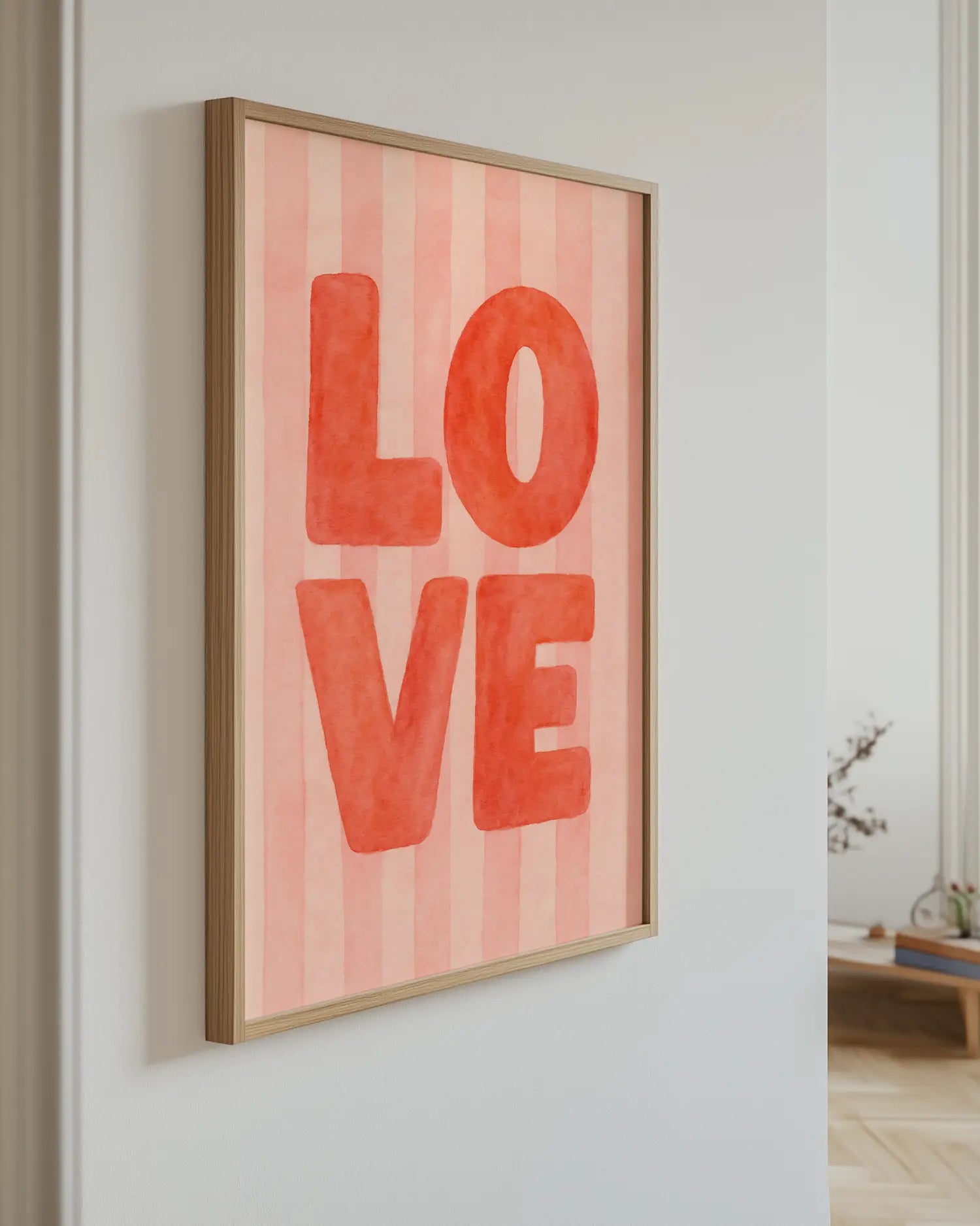 Framed artwork with 'LOVE' on a pink striped background in a room.