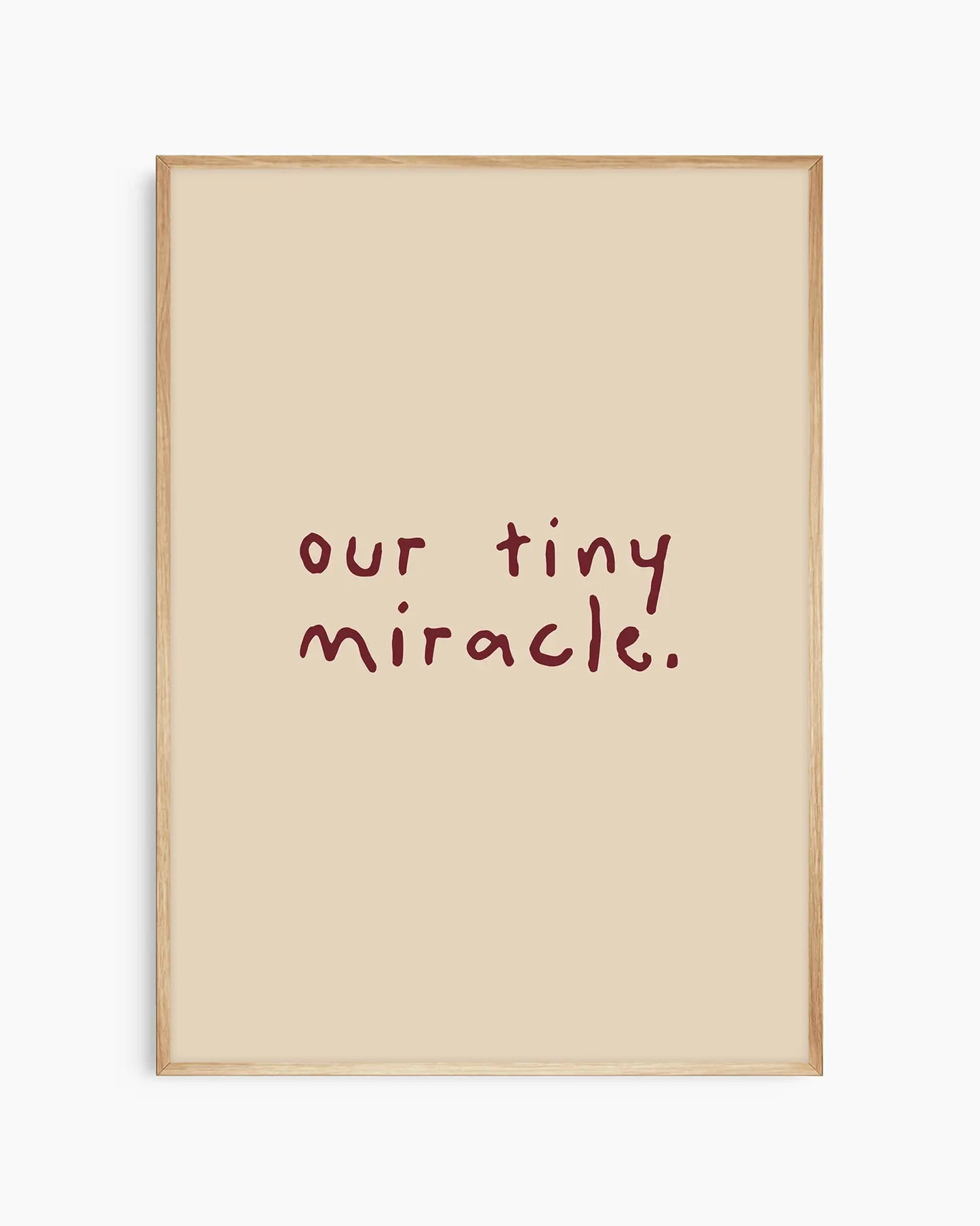 Beige nursery poster with 'our tiny miracle.' text in brown framed in an oak frame.