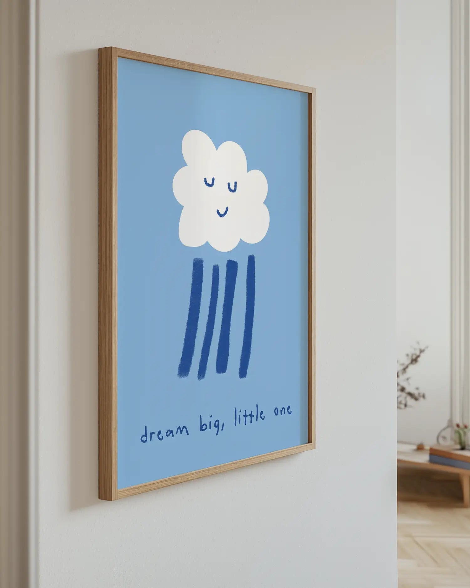 Framed artwork with a cloud design and text on a blue background, hanging on a wall.