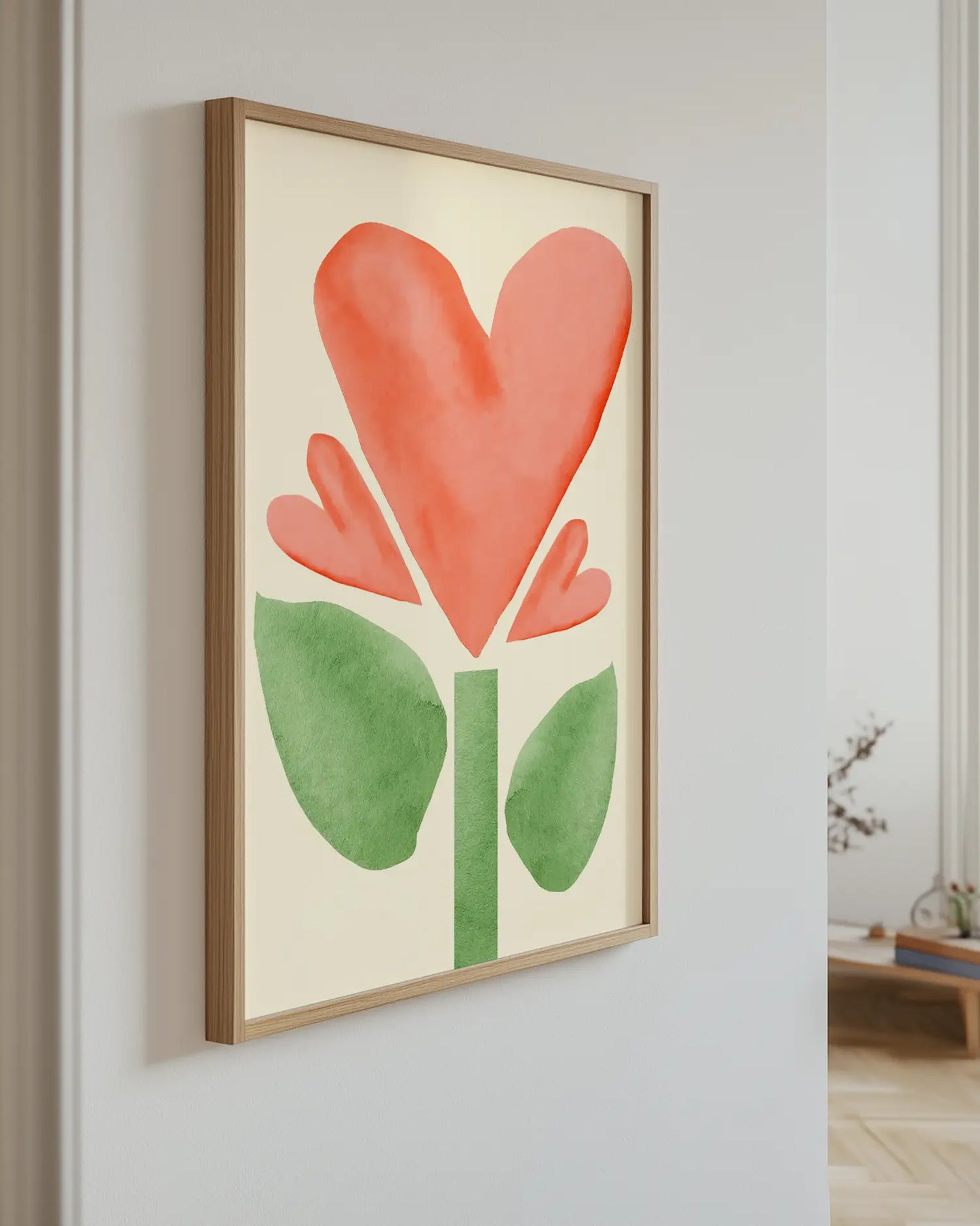 Artwork of a red flower with green leaves on a light wall.