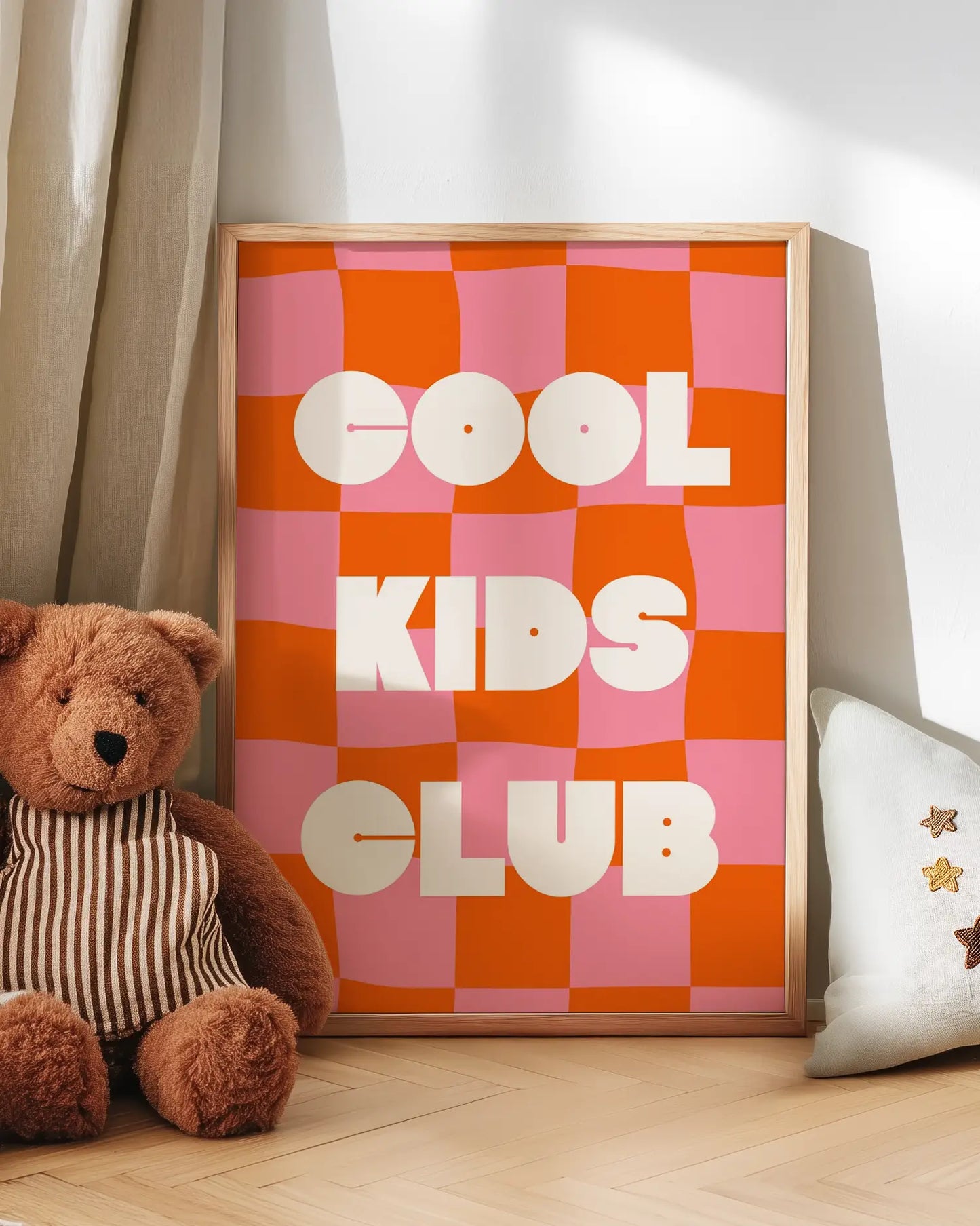 Checkered sign with 'Cool Kids Club' text next to a teddy bear on a wooden floor.