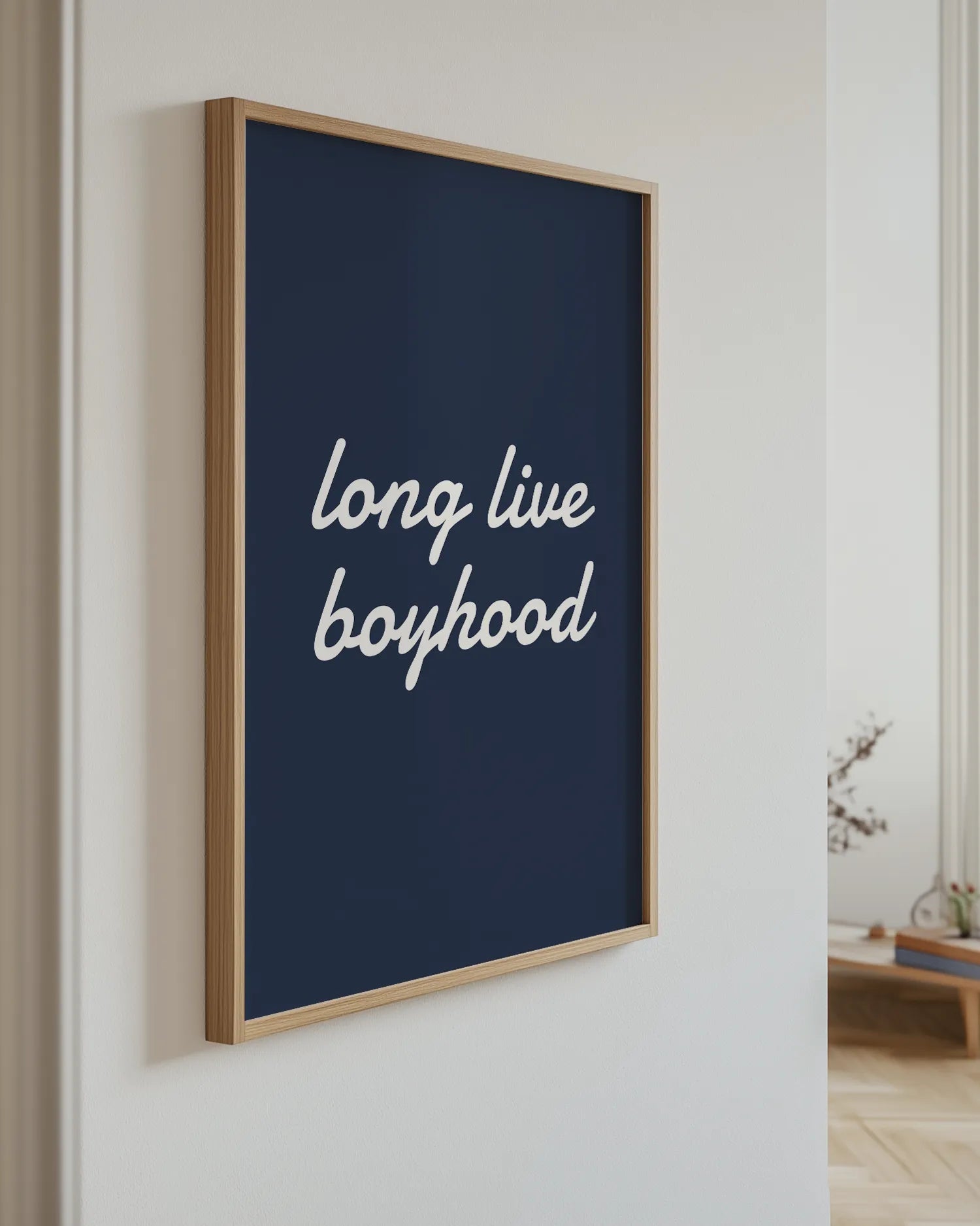 Framed artwork with 'long live boyhood' text on a blue background, mounted on a wall.
