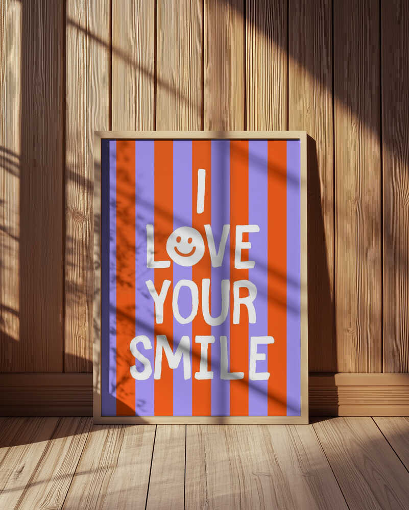 Framed poster with the text 'I love your smile' on a striped background, leaning against a wooden wall.