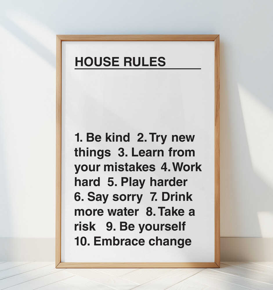 Inspirational text poster with the headline “House Rules” and motivational words in bold black typography, framed in light wood and leaning against a white wall. Perfect statement print for modern home or office decor.